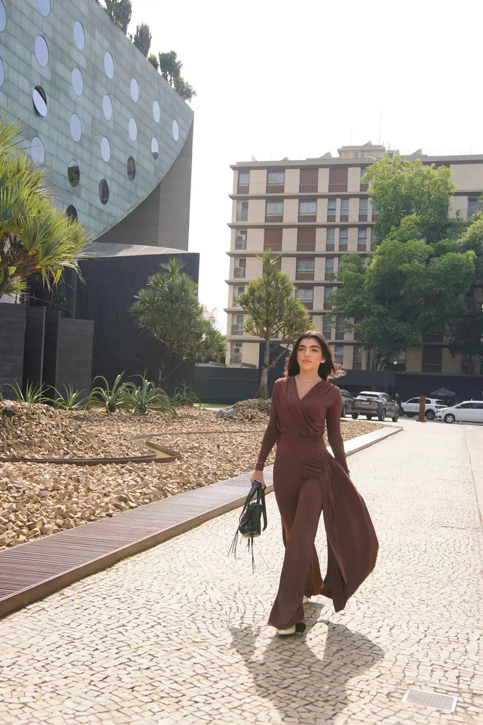 Dra. Bianca Rodrigues Neto caminhando ao ar livre, de vestido marrom
