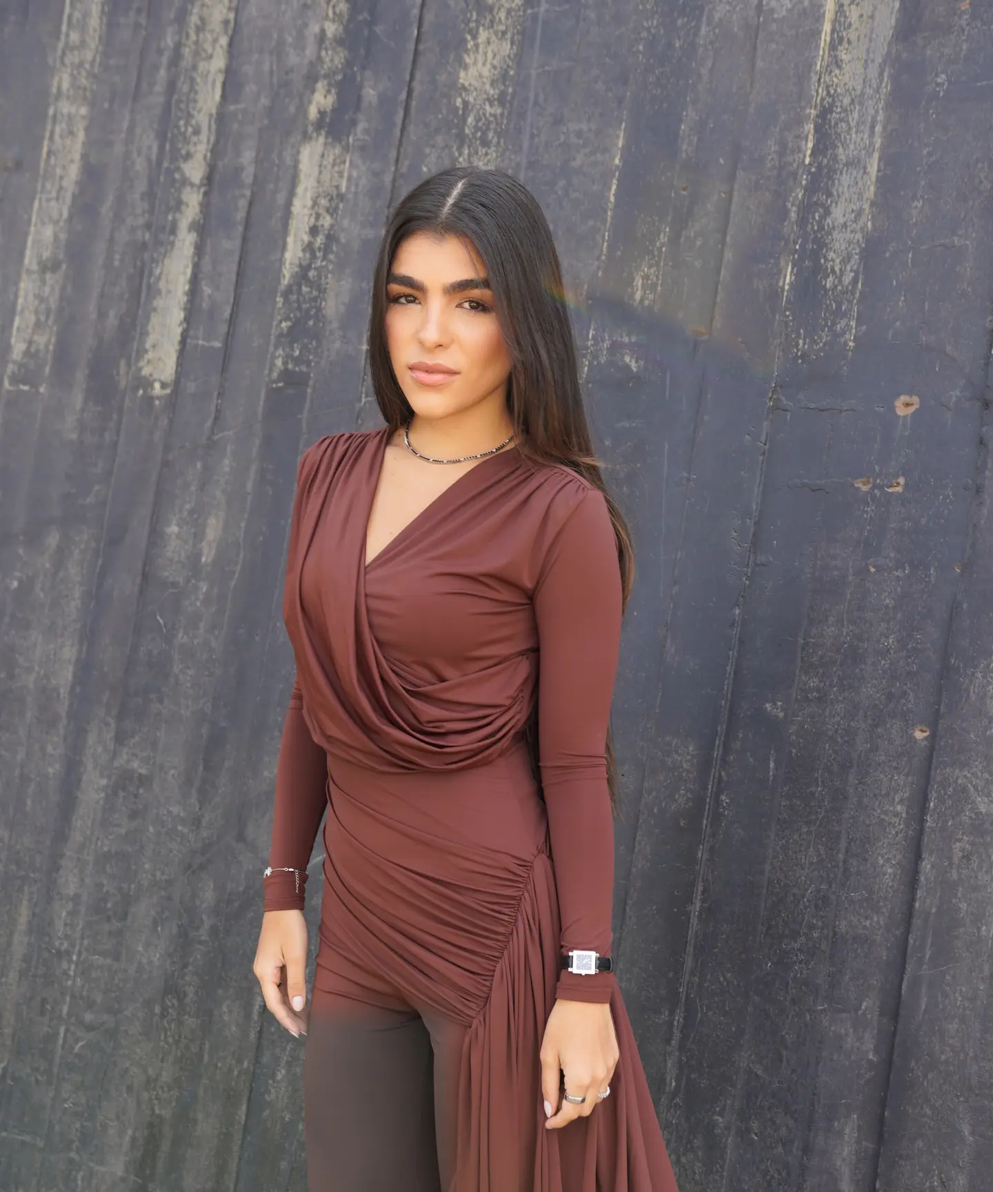 Dra. Bianca Rodrigues Neto de vestido marrom diante de uma parede escura